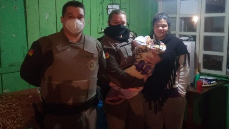 Policiais Militares com o bebê salvo em seu colo.