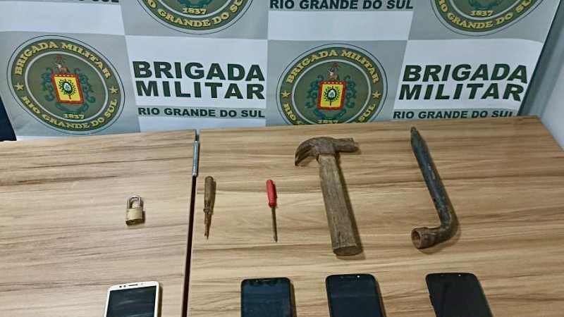 Material apreendido a frente do banner institucional da Brigada Militar.