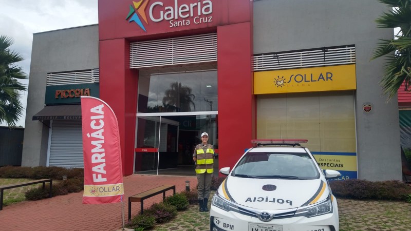 Policial militar ao lado da viatura.
