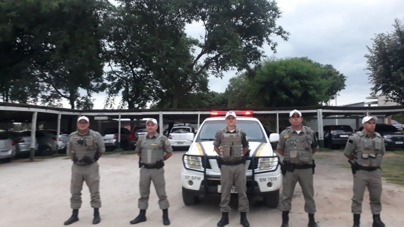Policiais militares perfilados a frente da viatura.