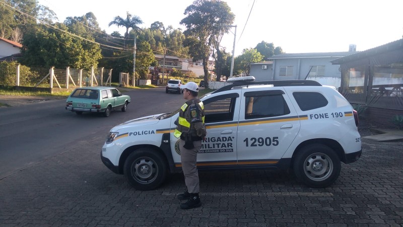 um policial militar em pé ao lado da viatura