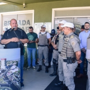 Militares estão de pé, observando um homem discursar