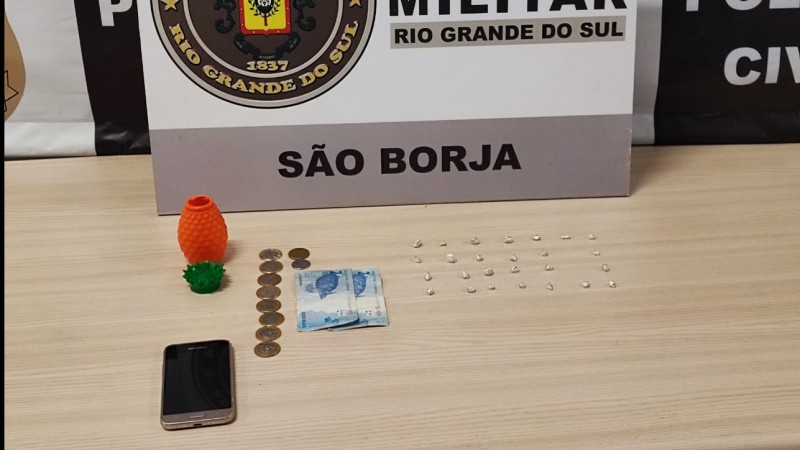 Drogas, celular e dinheiro em cima de uma mesa