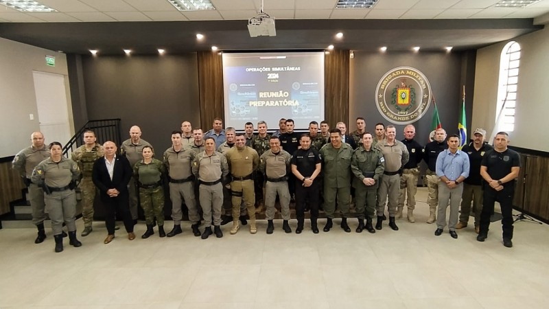 A foto mostra as autoridades em pé, no auditório onde foi realizada a reunião 