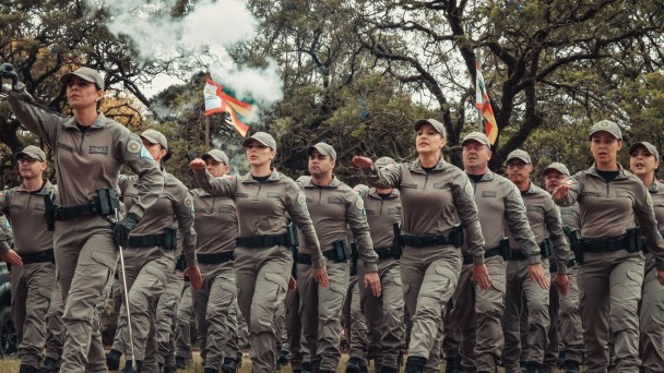 Foto mostra os policiais militares formandos entrando em campo aberto durante a cerimônia