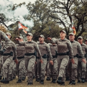 Foto mostra os policiais militares formandos entrando em campo aberto durante a cerimônia