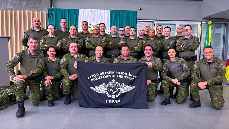 Foto mostra os formandos perfilados segurando uma bandeira do curso.