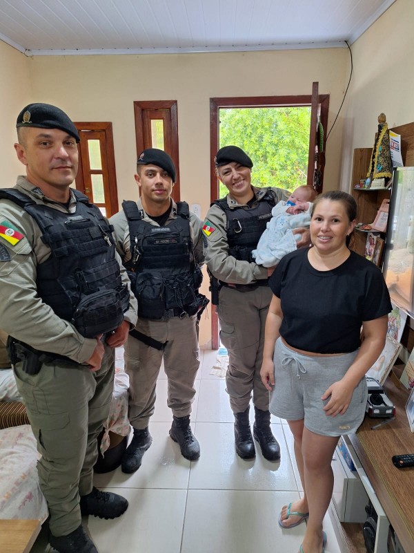 Foto mostra a mãe e o bebê posando para a foto junto à equipe