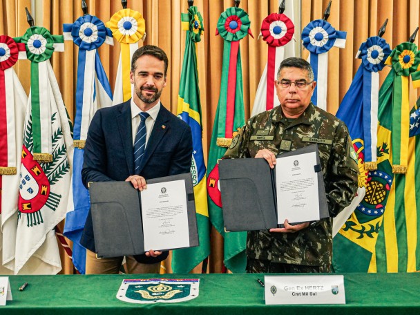 Governador Eduardo Leite e general Hertz Pires do Nascimento posam para foto segurando os termos de doação assinados.