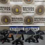 Armas, placas de veículos, munições, luvas, celular sobre uma mesa eo brasão da BM
