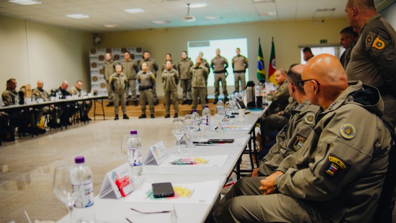 Imagem mostra os militares dispostos em círculo assistindo a explanação de um gruipo em pé no palco