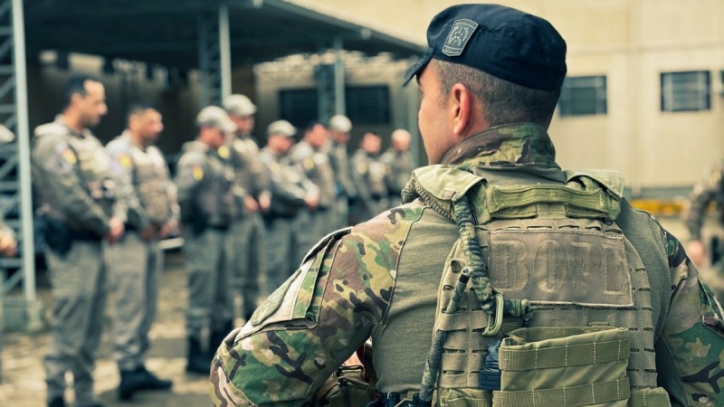 operador do BOPE de costas ao fundo policiais militares recebendo instru&ccedil;&atilde;o 