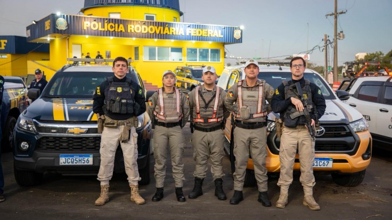 Foto mostra tr&ecirc;s policiais militares da BM ladeados por dois PRFs