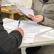 Policial militar do Departamento de Pessoal e Finanças analisa documentos apresentados por um candidato durante a etapa de verificação documental para ingresso no Curso Superior de Polícia Militar.