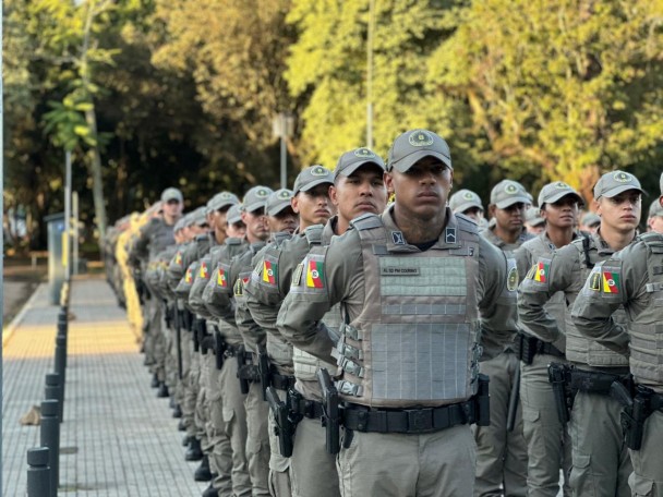 Imagem mostra alunos-soldados da Brigada Militar alinhados em formação. Os policiais utilizam uniforme operacional cáqui, colete balístico e boné institucional durante a cerimônia.